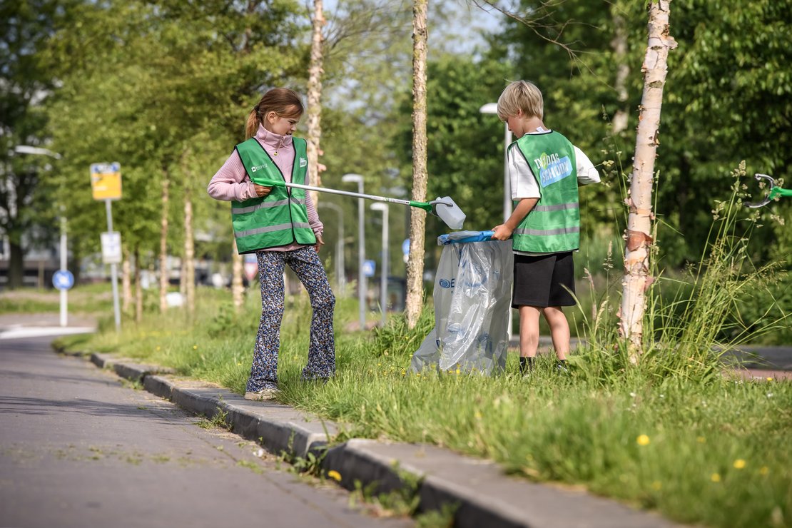 Twee kinderen die afval aan het oprapen zijn om de openbare ruimte schoon te maken